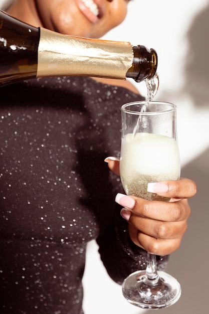 Foto gratuita donna del primo piano che versa un bicchiere di champagne