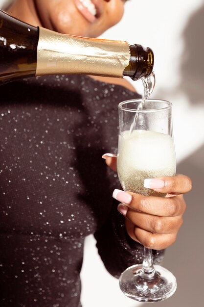 Крупным планом женщина наливает бокал шампанского