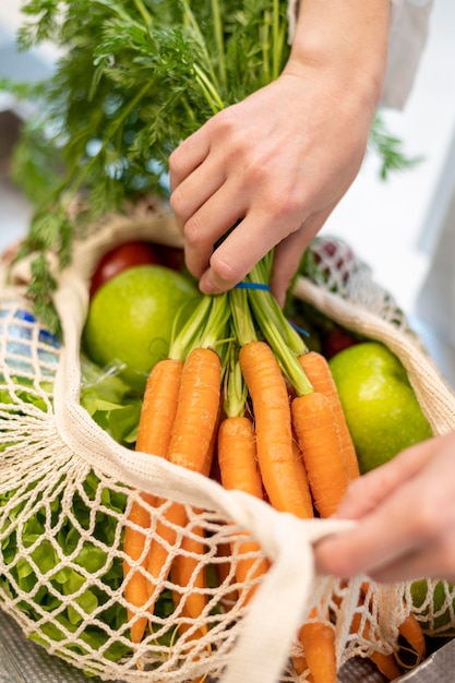 Бесплатное фото Женщина крупного плана кладя продукты в многоразовую сумку