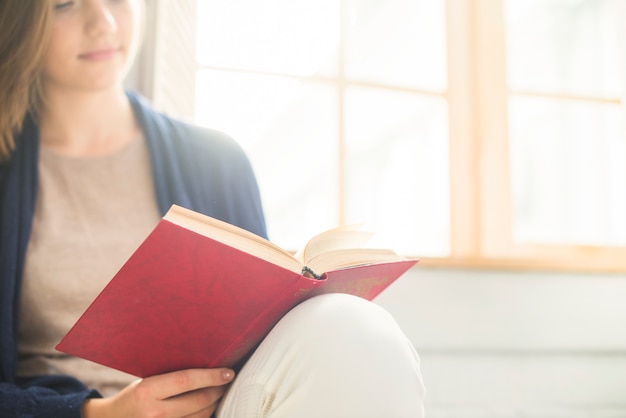 Foto gratuita primo piano di un libro di lettura della donna a casa