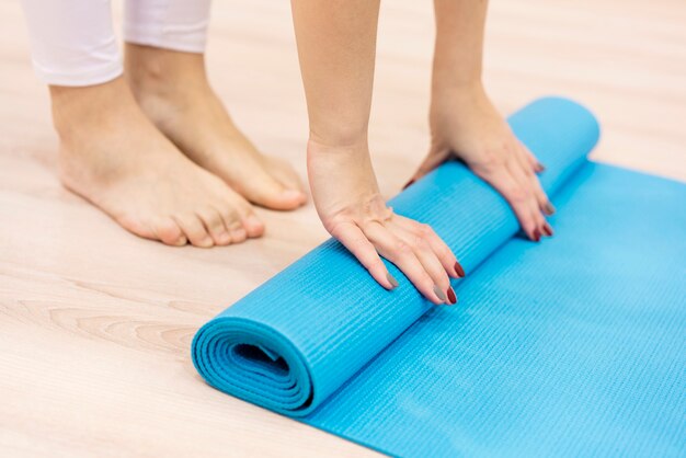 Close-up woman rolling fitness mat after working out