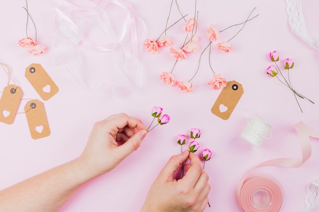 Close-up of woman's hand arranging the flower against pink background