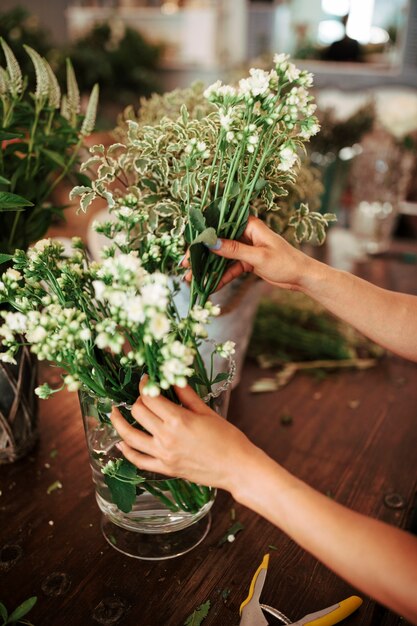 Close-up of a woman's hand arranging flowers in vase