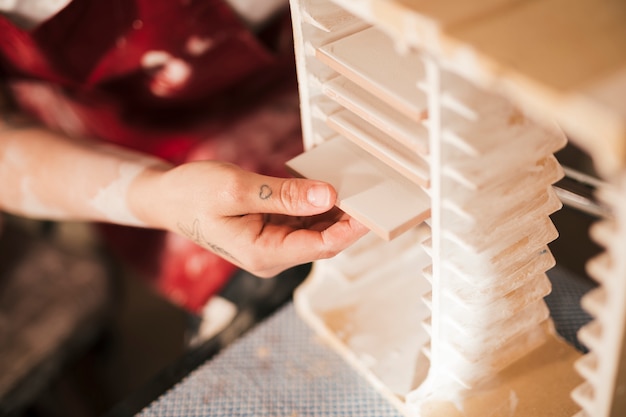 Close-up of a woman's hand arranging the painted tiles in the rack