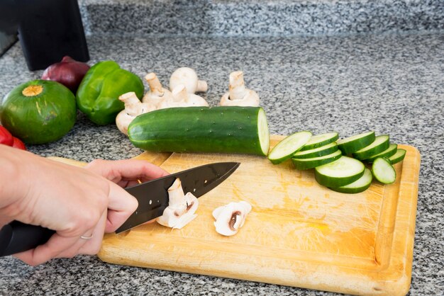 Close-up of woman's hand cutting mushroom slices with knife