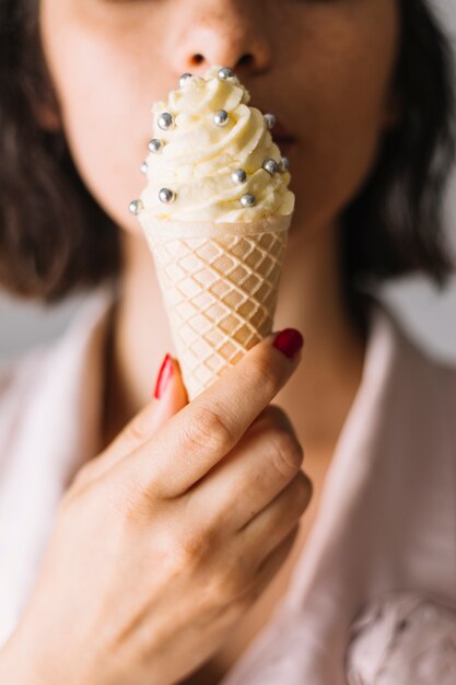 Крупным планом руки женщины едят мороженое с серебряными шариками