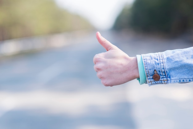 Close-up of woman's hand hitchhiking at countryside road