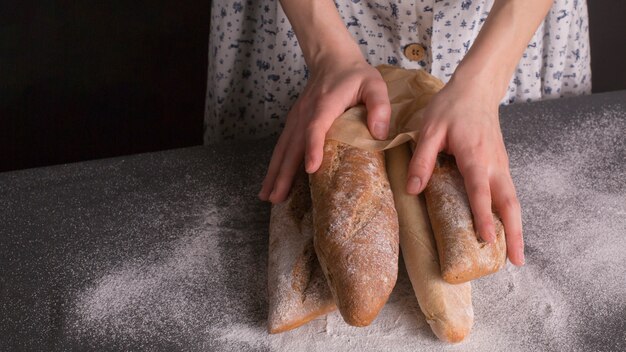 キッチンカウンターで焼きたてのパンを持っている女性の手のクローズアップ