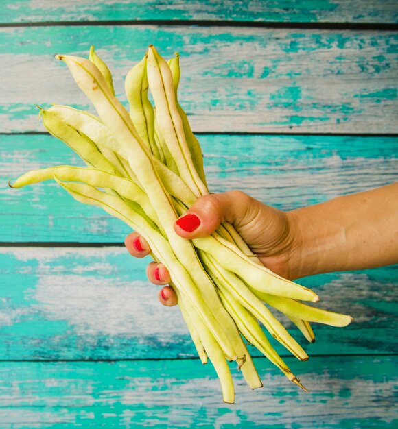 Close-up of a woman's hand holding beans against weathered wooden plank