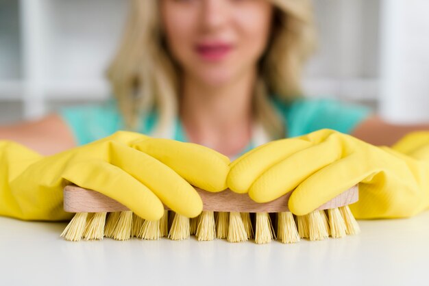 Close-up of woman's hand holding brush during cleaning white table