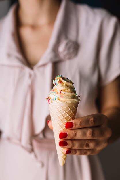 Close-up of woman's hand holding ice cream cone with sprinkles