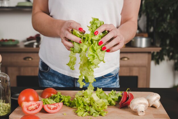 Close-up of woman's hand holding lettuce in hands over chopping board