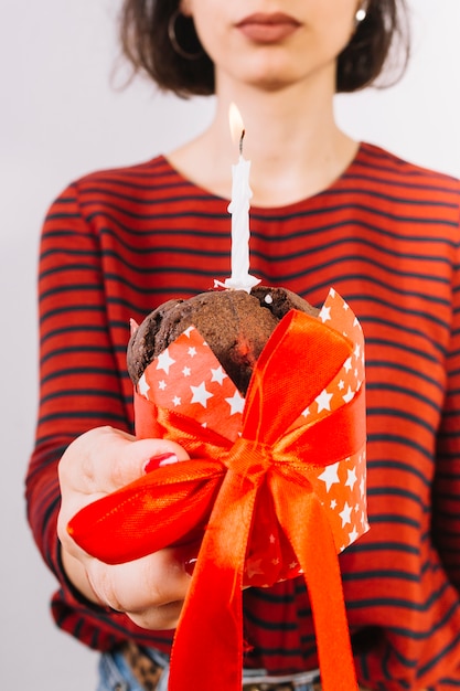 Close-up of a woman's hand holding muffins tied with red ribbon