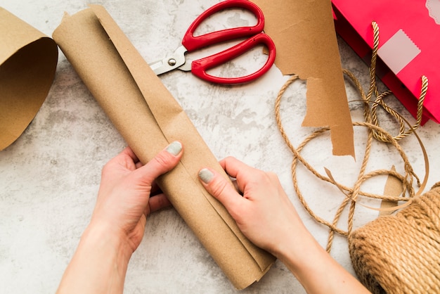 Close-up of woman's hand holding rolled up brown paper