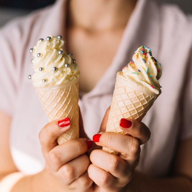 Close-up of a woman's hand holding two different type of ice cream cones in her hand