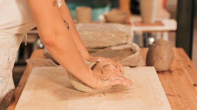 Close-up of woman's hand kneading clay on the board