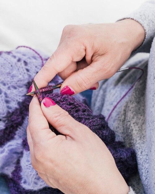 Close-up of woman's hand knitting purple wool