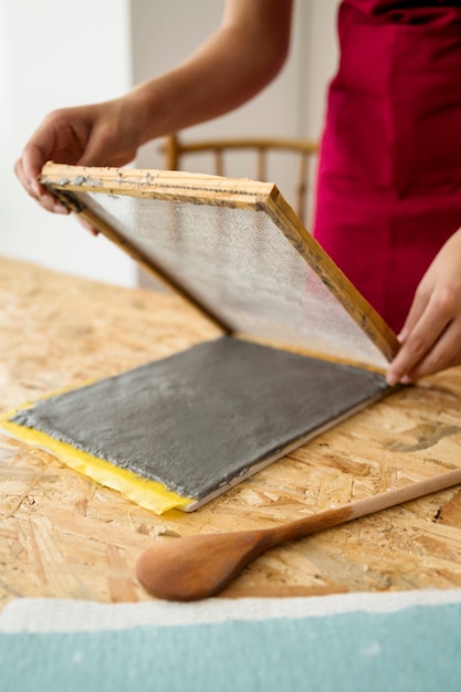 Close-up of a woman's hand making paper with pulp