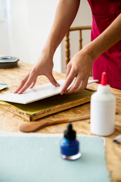 Close-up of woman's hand placing cover on paper pulp over desk