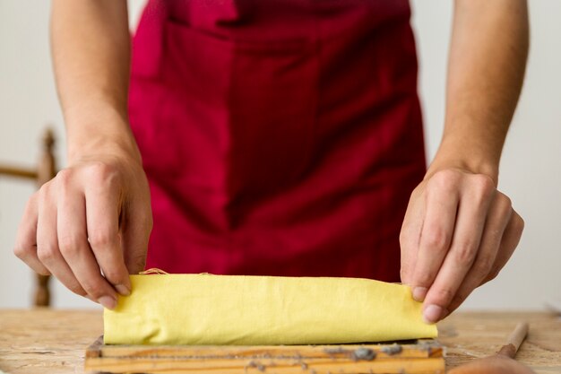 Close-up of a woman's hand placing yellow cloth on paper pulp