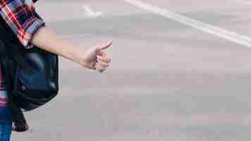 Free photo close-up of woman's hand showing thumb up gesture on street