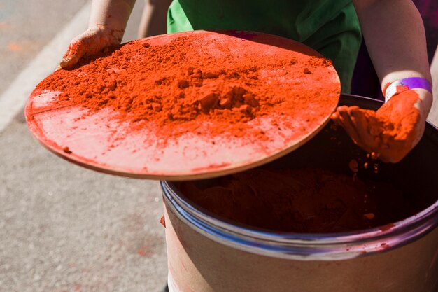 Close-up of woman's hand taking holi color powder from drum