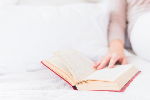 Close-up of woman's hand touching book on bed