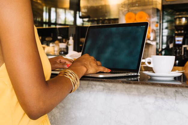 Close-up of woman's hand typing on digital tablet at cafe