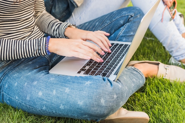 Close-up of a woman's hand using laptop in park