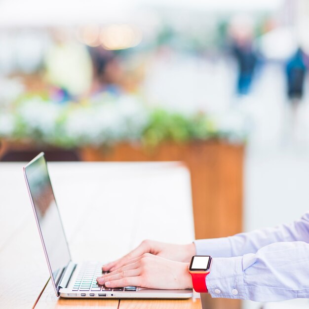 Close-up of a woman's hand using laptop over wooden desk