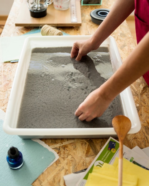 Close-up of a woman's hand with paper pulp in tray