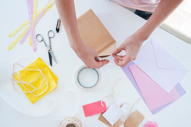 Close-up of woman's hand wrapping the gift box on table