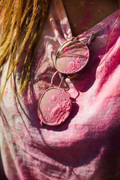 Close-up of woman's t-shirt and sunglasses mess with holi color