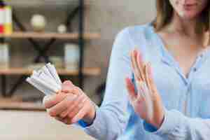 Free photo close-up of woman saying no holding bunch of cigarettes in hand