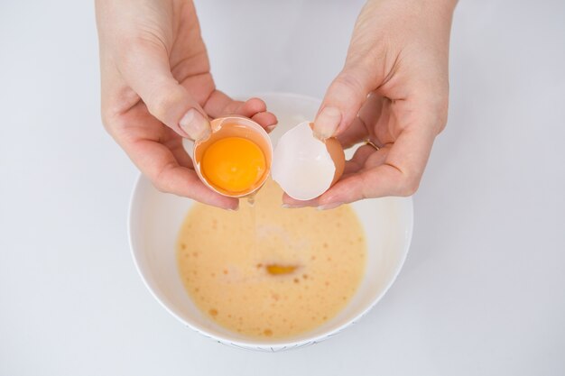 Крупным планом женщина, отделяющая яйцо на кухонном столе