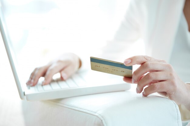 Close-up of woman shopping online with credit card and laptop