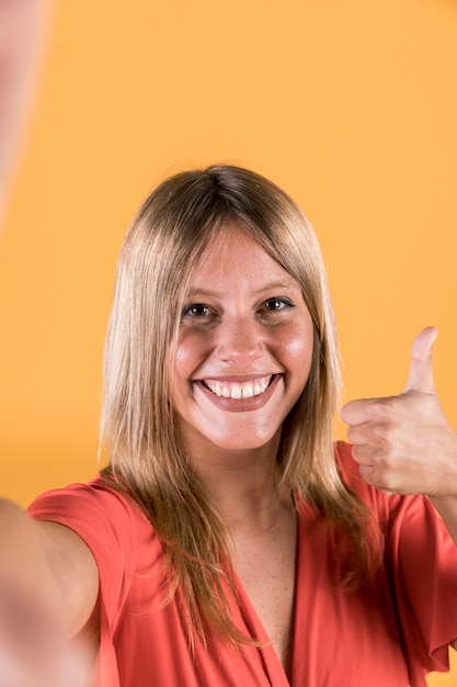 Close-up of woman showing thumb up looking at camera