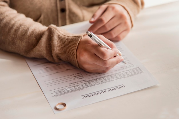 Close-up woman signing divorce agreement