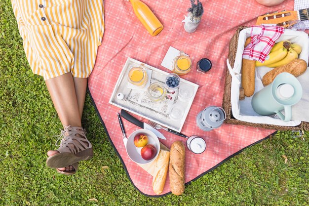 Close-up of woman sitting near the picnic basket on blanket