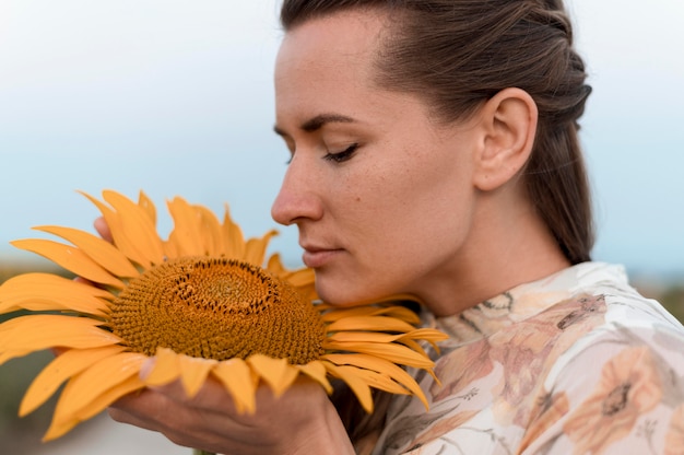 Free photo close-up woman smelling sunflower