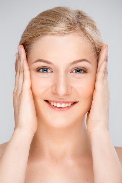 Close up woman smiling touching perfect skin