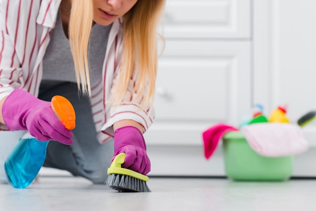 Close-up woman spray cleaning floor