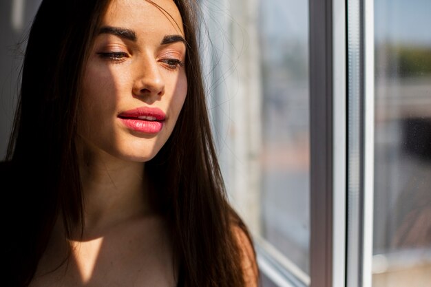 Close-up woman standing  looking at window