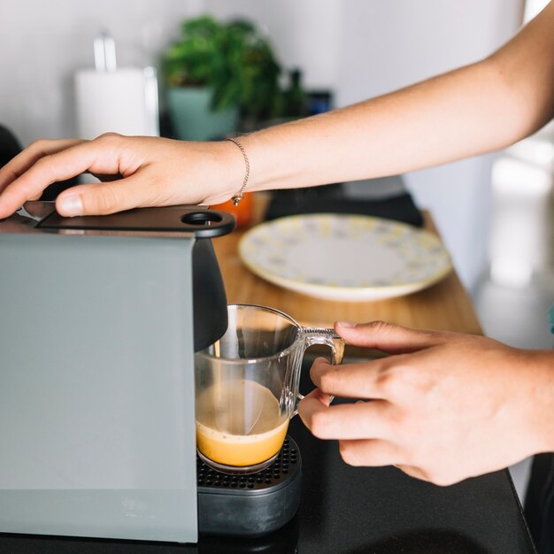 커피 기계에서 커피를 복용하는 여자의 근접 촬영