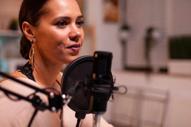 Close up of woman talking on microphone during streaming. On-air online production internet broadcast show host streaming live content, recording digital social media communication