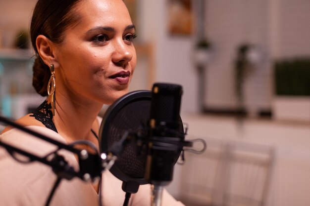 Close up of woman talking on microphone during streaming. On-air online production internet broadcast show host streaming live content, recording digital social media communication