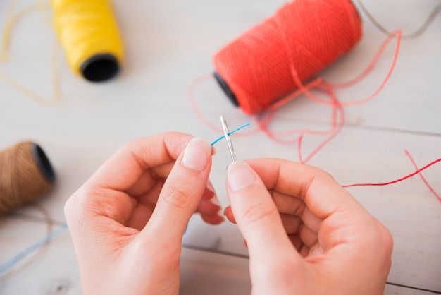 Close-up of a woman trying to put thread into needle hole