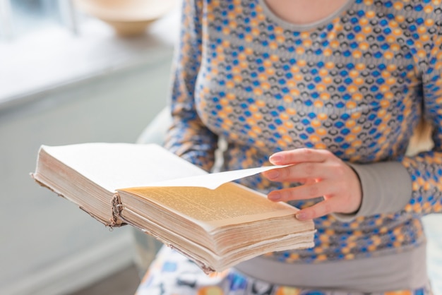 Foto gratuita primo piano di una donna che gira la pagina del libro tra le mani