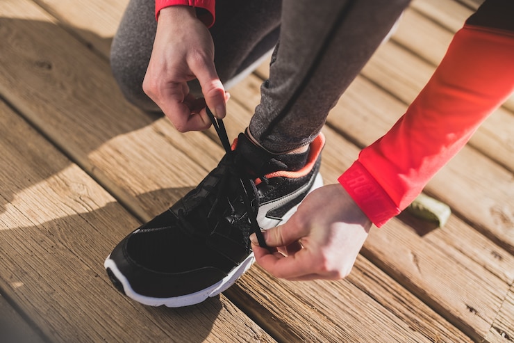 無料Photo close-up of woman tying her shoelaces on wooden floor