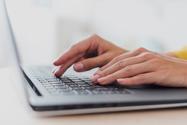 Free photo close-up woman typing on laptop's keyboard